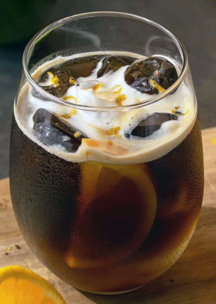 espresso and tonic served with a slice of orange over ice in a glass