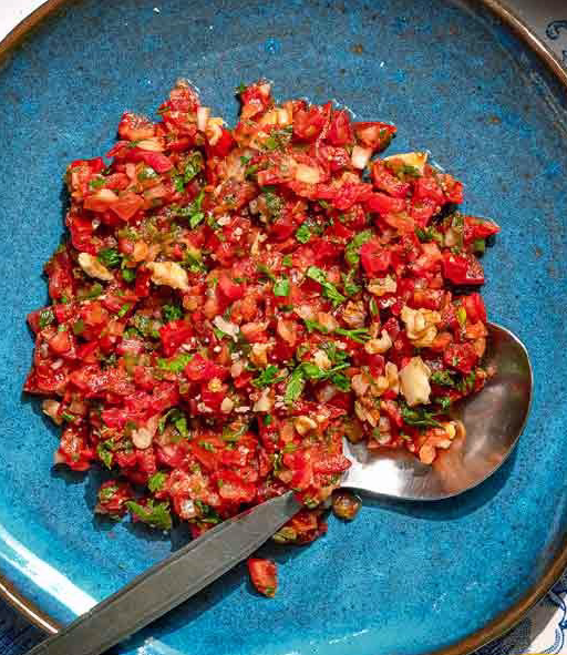 ezme spicy Turkish salad on a blue plate with a spoon