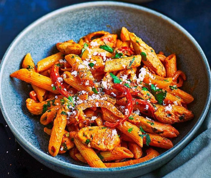Penne pasta in a fajita-flavoured tomato sauce with bell peppers served in a blue bowl