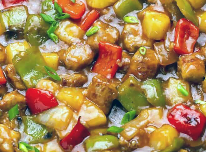 Filipino sweet and sour pork stew with pineapple and bell peppers served on a plate