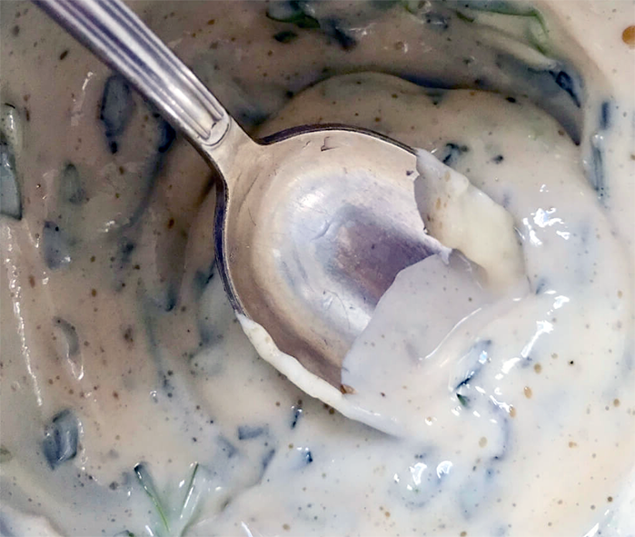 Spoon inserted into a bowl of maitre d'hotel sauce