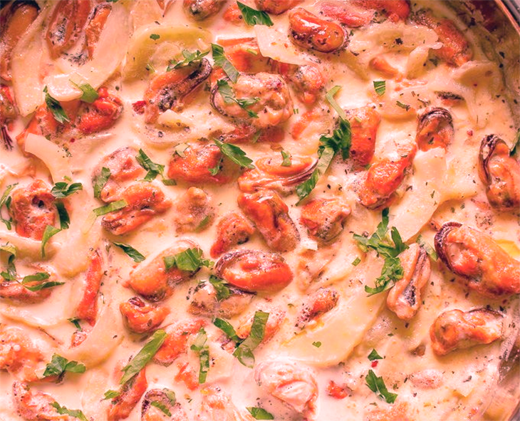 Dish of mussel meats in a pink tinged allemande sauce base