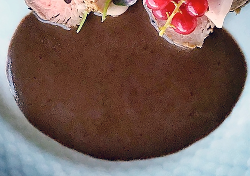 port wine sauce poured on a blue plate near meat medallions