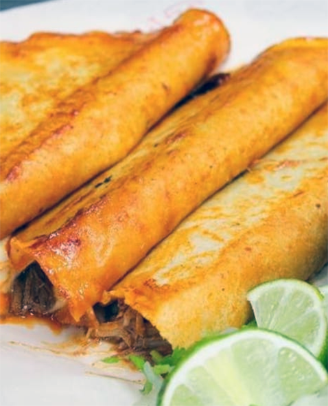 crab meat flautas served on a plate with lime wedges