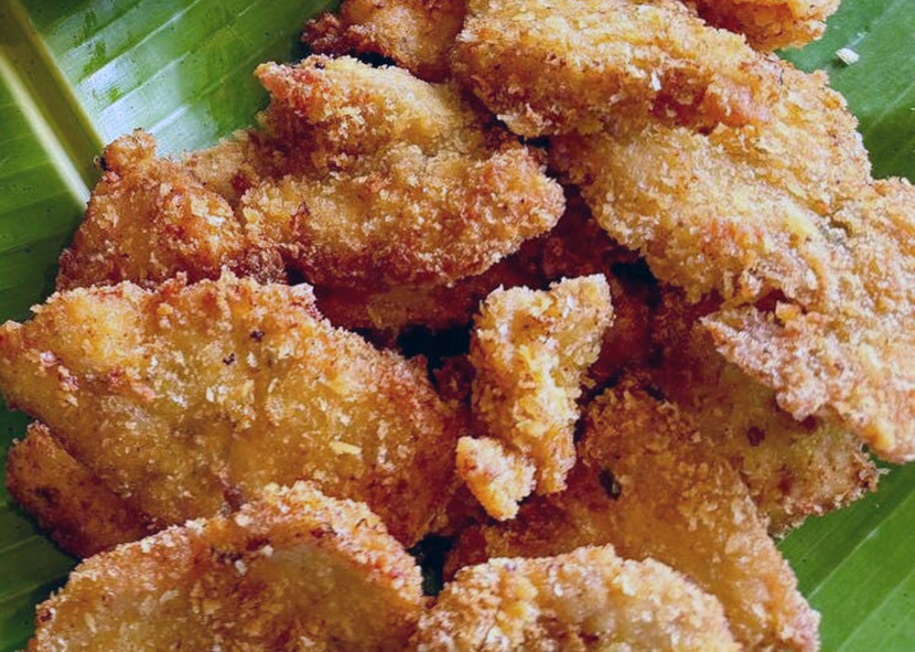 breaded and fried papaya chunks on a banana leaf