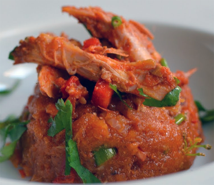 chicken pieces and vegetables served on a mound of gari cooked in the chicken cooking liquid