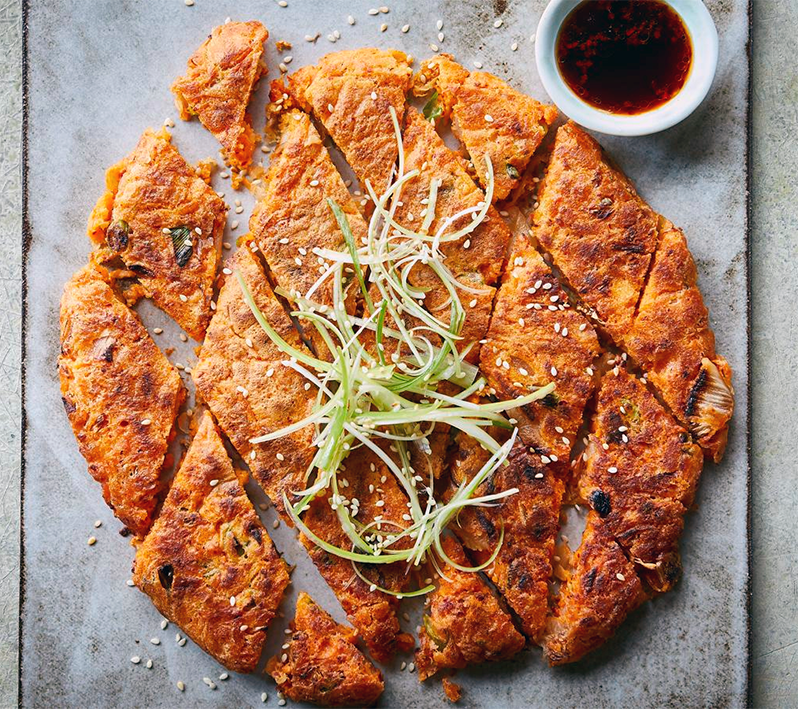 gimchijeon korean kimchi pancake cut into diamonds and served on a grey-painted table