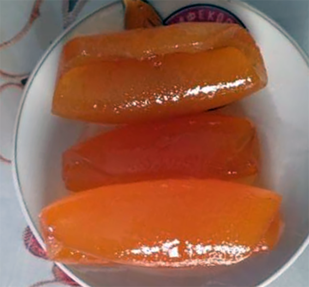 three rolled bitter lemon peel pieces in syrup on a plate