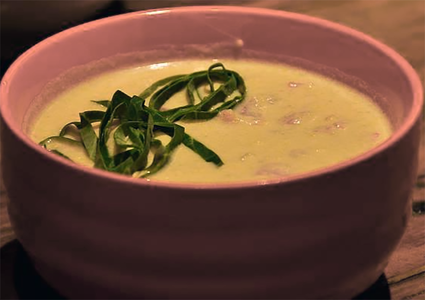 green mealie soup served in a bowl garnished with shredded basil leaves