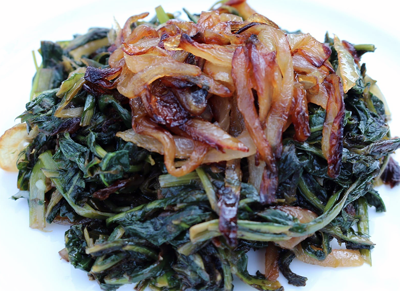dandelion leaves in oil served topped with fried onions