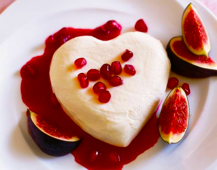 Honey cream heart on a bed of raspberry coulis surrounded by fig wedges and garnished with pomegranate arils