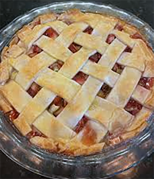 japanese knotweed pie in a glass dish with a lattice-work pastry lid