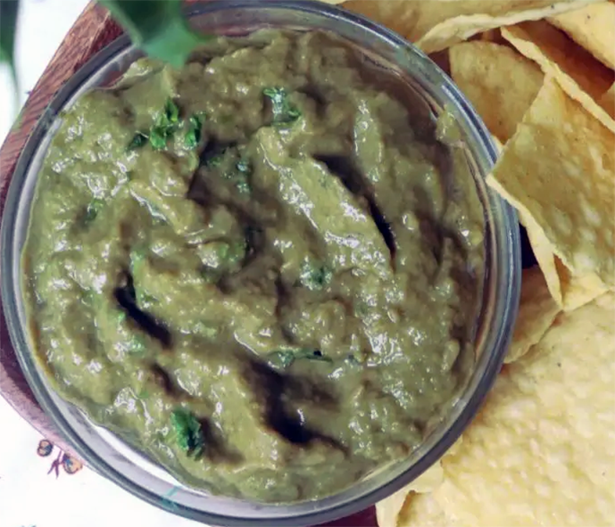 Japanese knotweed salsa verde in a glass bowl next to some corn chips