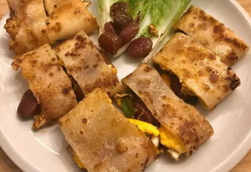 Chinese kao lengimian, cold grilled noodles with a filling of egg and sausages sliced into rounds and served on a plate