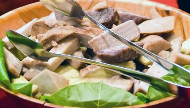 parboiled and fried mixed root vegetables served on a wooden bowl on a bed of arrowroot leaves