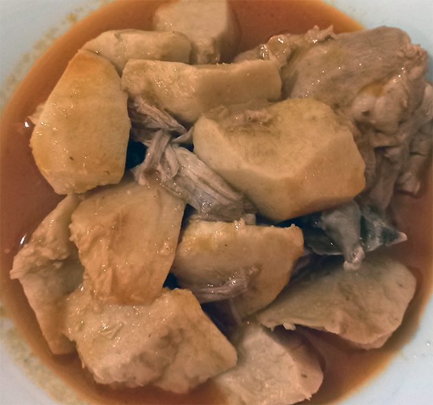 kolkas, stew of taro and chicken in a tomato and celery base served in a white bowl