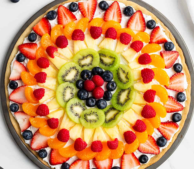 sweet pizza style base served topped with summer fruit arranged in a decorative pattern