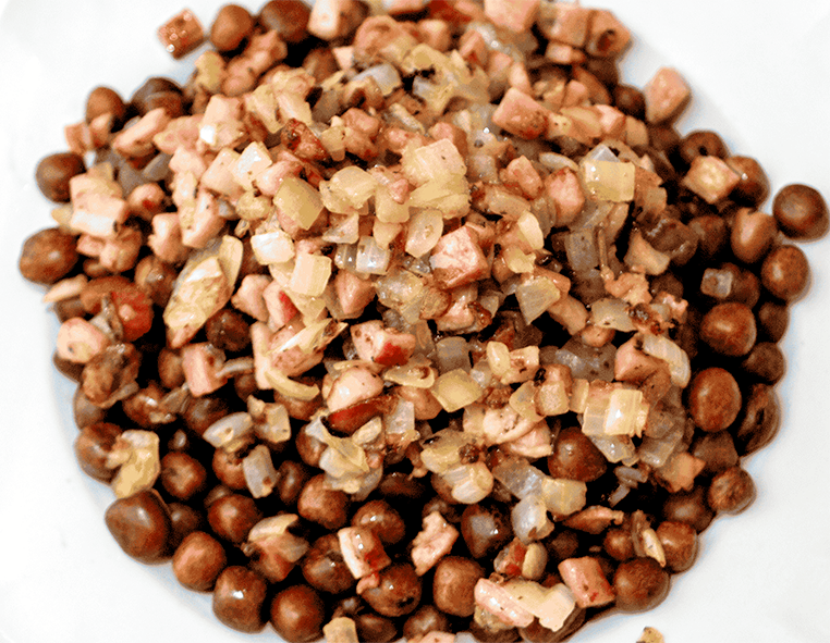 mixed bacon, onions and grey peas piled on a white plate