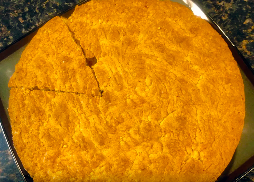 large liberian shortbread on a baking tray with a wedge cut into it