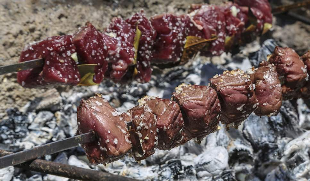 Madeiran espetada, beef kebabs cooking over hot coals