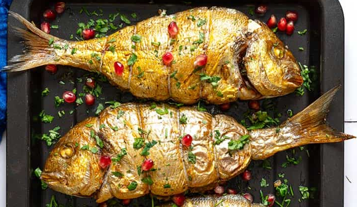 Mahi shekam por, Persian roasted stuffed fish garnished with pomegranate seeds and presented on a baking tray