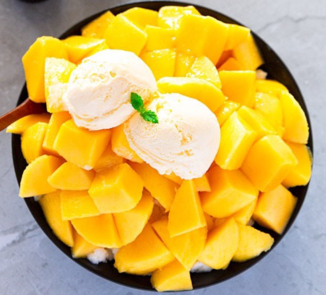 mango shaved ice in a bowl served topped with cubed mangos and ice cream