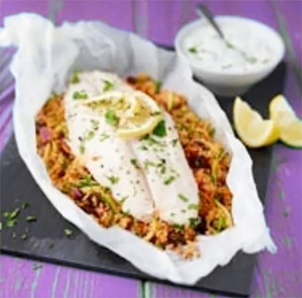 fish cooked in a greaseproof paper parcel with vegetable couscous with the parcel opened to show the contents