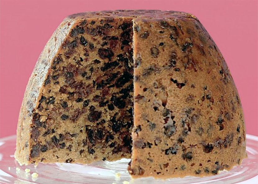 pale version of Christmas plum pudding turned out onto a plate and with wedge removed