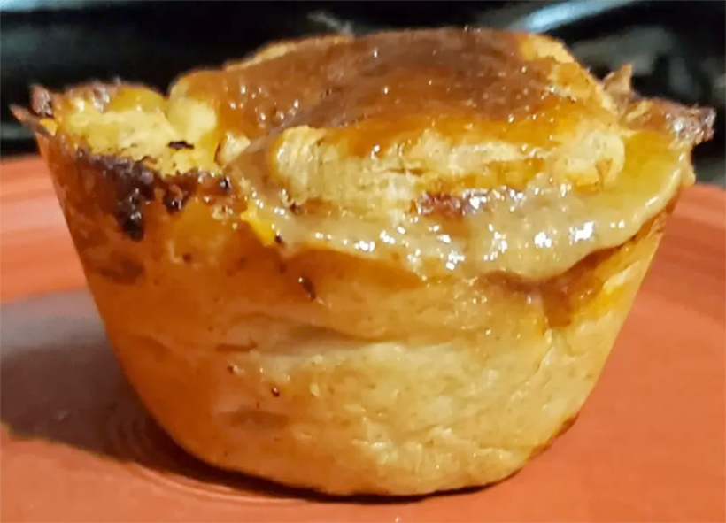 individual New Zealand meat pie on a plate with a gravy topping