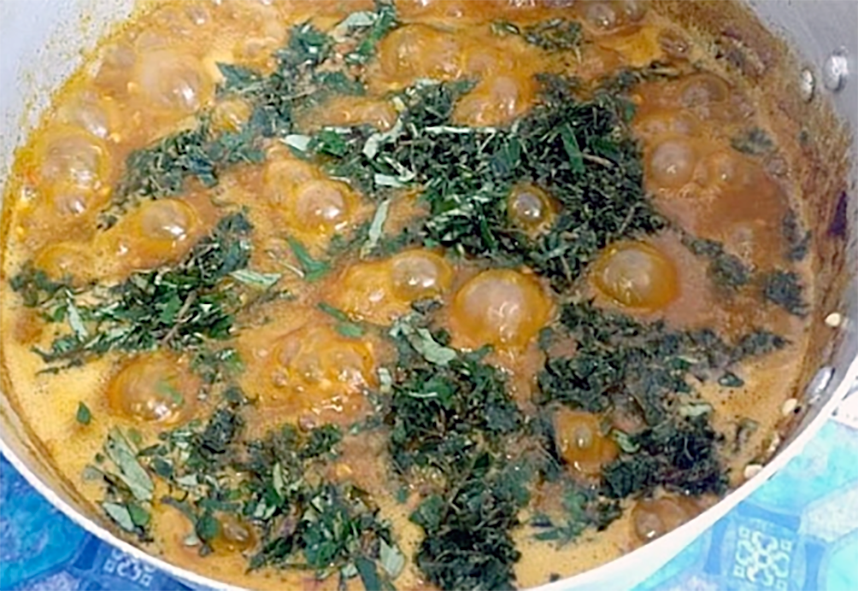 simmering ogbono soup topped with shredded ugwu (pumpkin leaves)