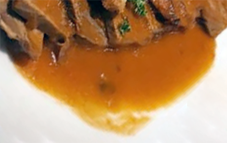 slices of beef on a white plate smothered in oude sauce