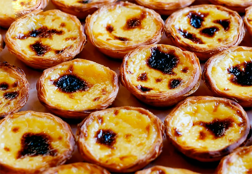 rows of pastel de belem egg tarts in a baker's window