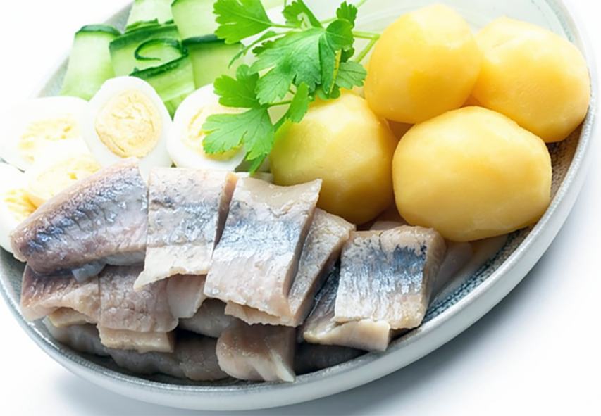 boiled salt herring and potatoes served wth boiled eggs, onions and parsley sprigs