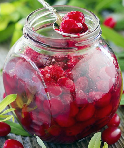 pickled cornelian cherries in a large glass jar