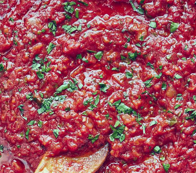 tomato sauce for pizza flavoured with emperor's mint stirred with a wooden spoon