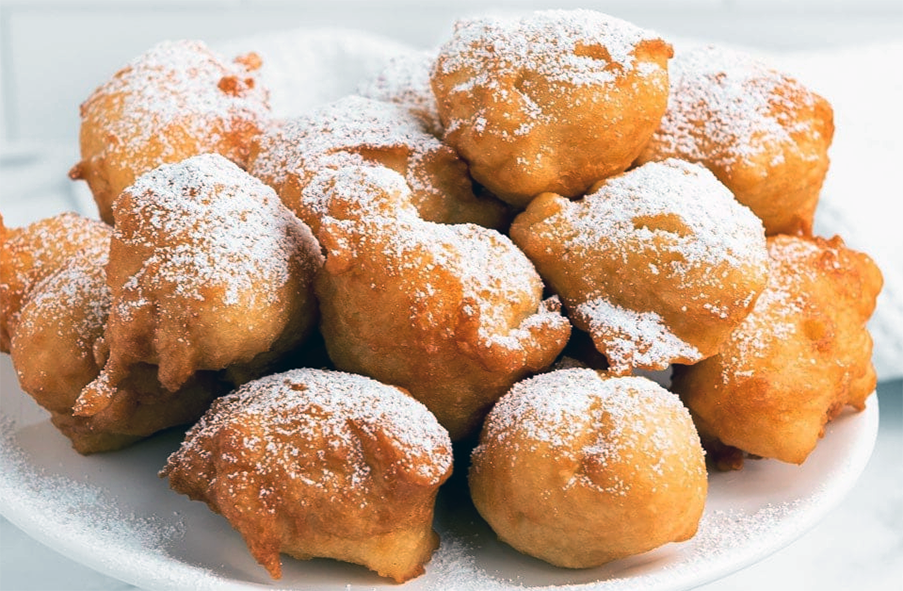 oliebollen doughnuts arranged on a plate and dusted with icing sugar
