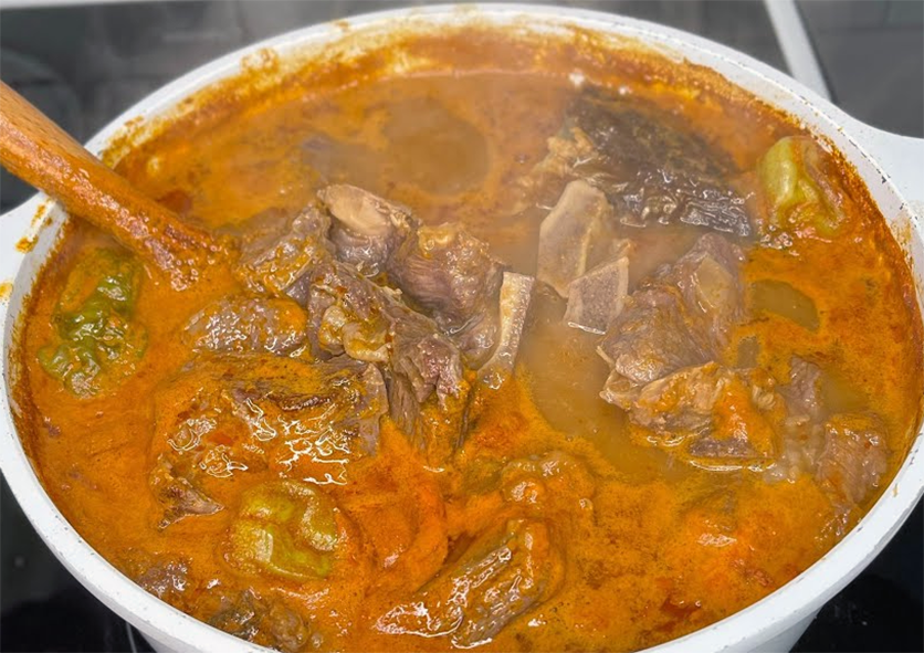 beef and plantain soup in a tomato and coconut milk base in a casserole dish