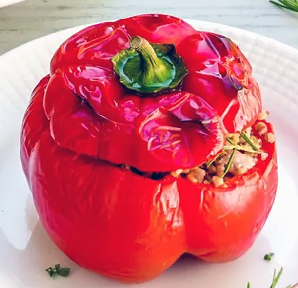 red bell pepper stuffed with meat and rice cooked under a grill served on a plate