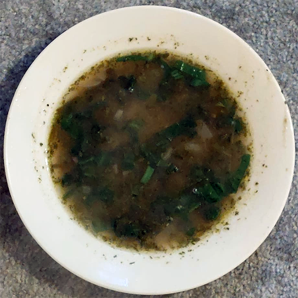 potato and spring greens soup in a white soup bowl