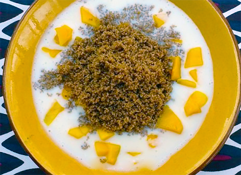chicken thighs with mango in white sauce served topped with fonio grains