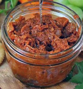 chutney of chopped and roasted pumpkin skin presented in a glass jar with a spoon