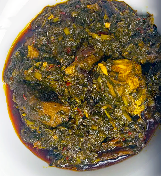 sweet potato greens, beef, chicken and fish cooked in red palm oil and served in a white bowl