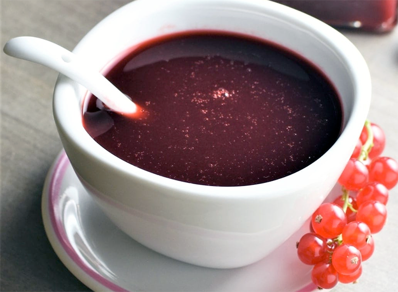 Redcurrant sauce in a white bowl with a ceramic spoon