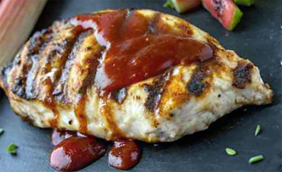 rhubarb-grilled chicken breast on a slate with pieces of rhubarb
