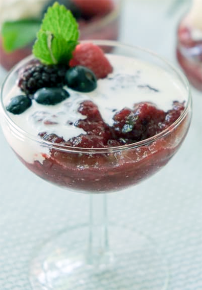 german red berry dessert served topped with cream in a champagne coupe with a sprig of mint