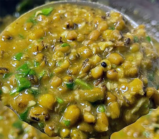 green mung bean bhaji on a large spoon