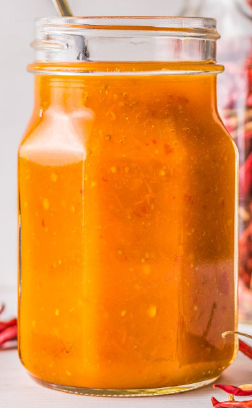 salsa amarilla in a glass jar with a metal spoon