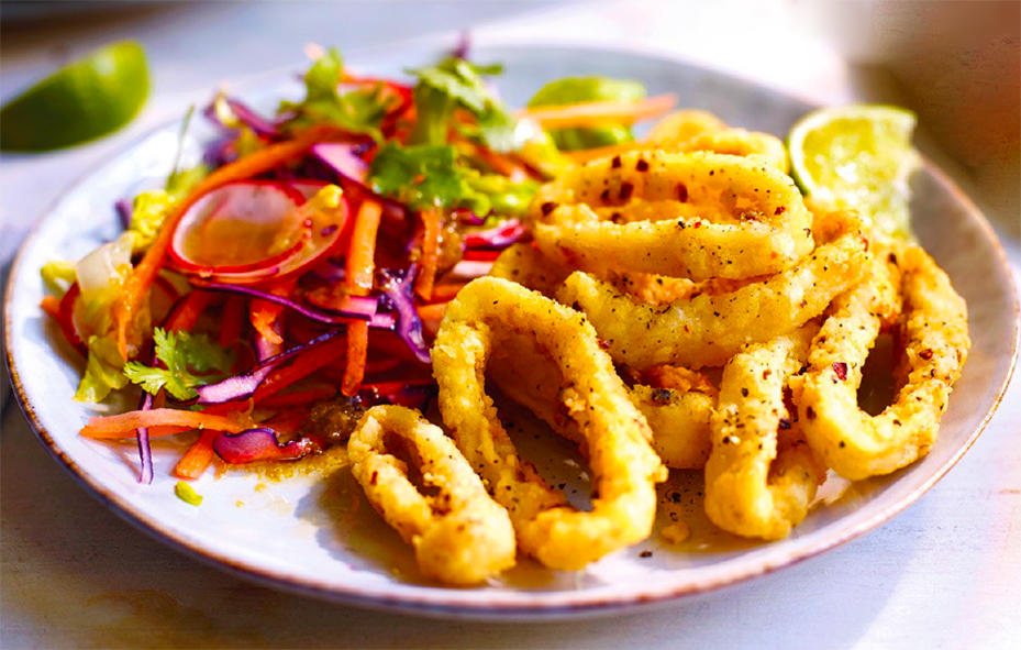 salt and pepper squid rings served on a plate and accompanied by a dressed salad