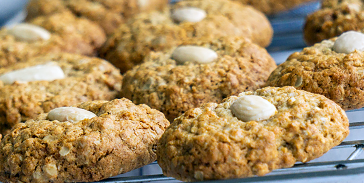 Scottish parkin biscuits with a blanched almond pressed in the centre cooling on a wire rack
