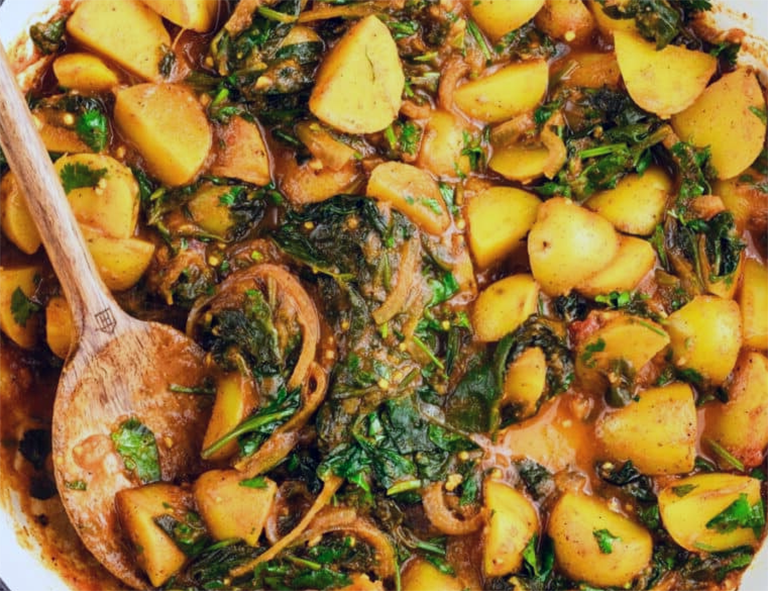 potato and sea aster leaf curry served garnished with coriander leaves